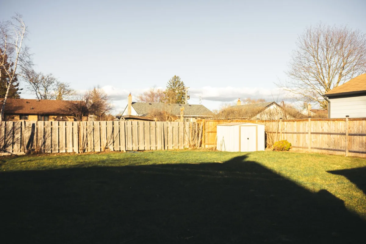 Garden shed standing on a lawn in a fenced Midwestern backyard
