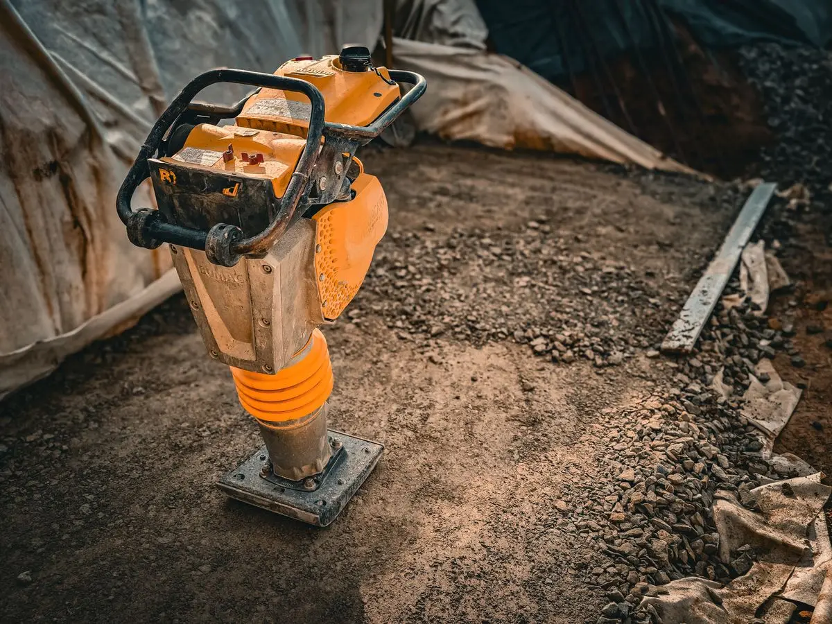 Vibratory compactor consolidating a gravel base before concrete is placed
