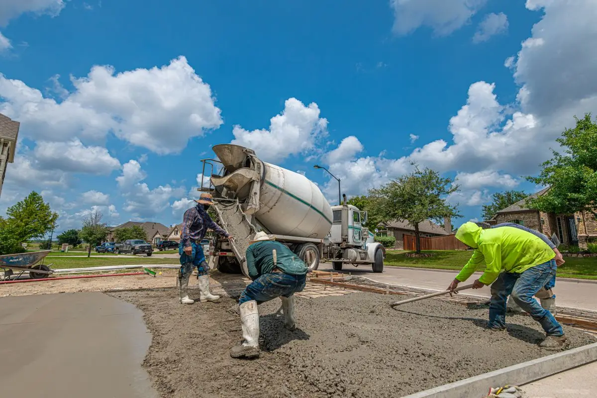 Crew placing and screeding concrete for a residential driveway